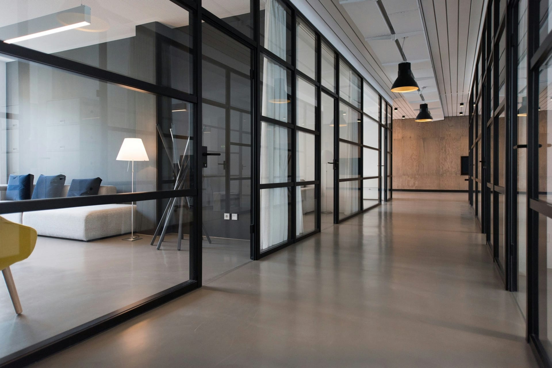 A commercial corridor with glass partitions and clean, polished flooring