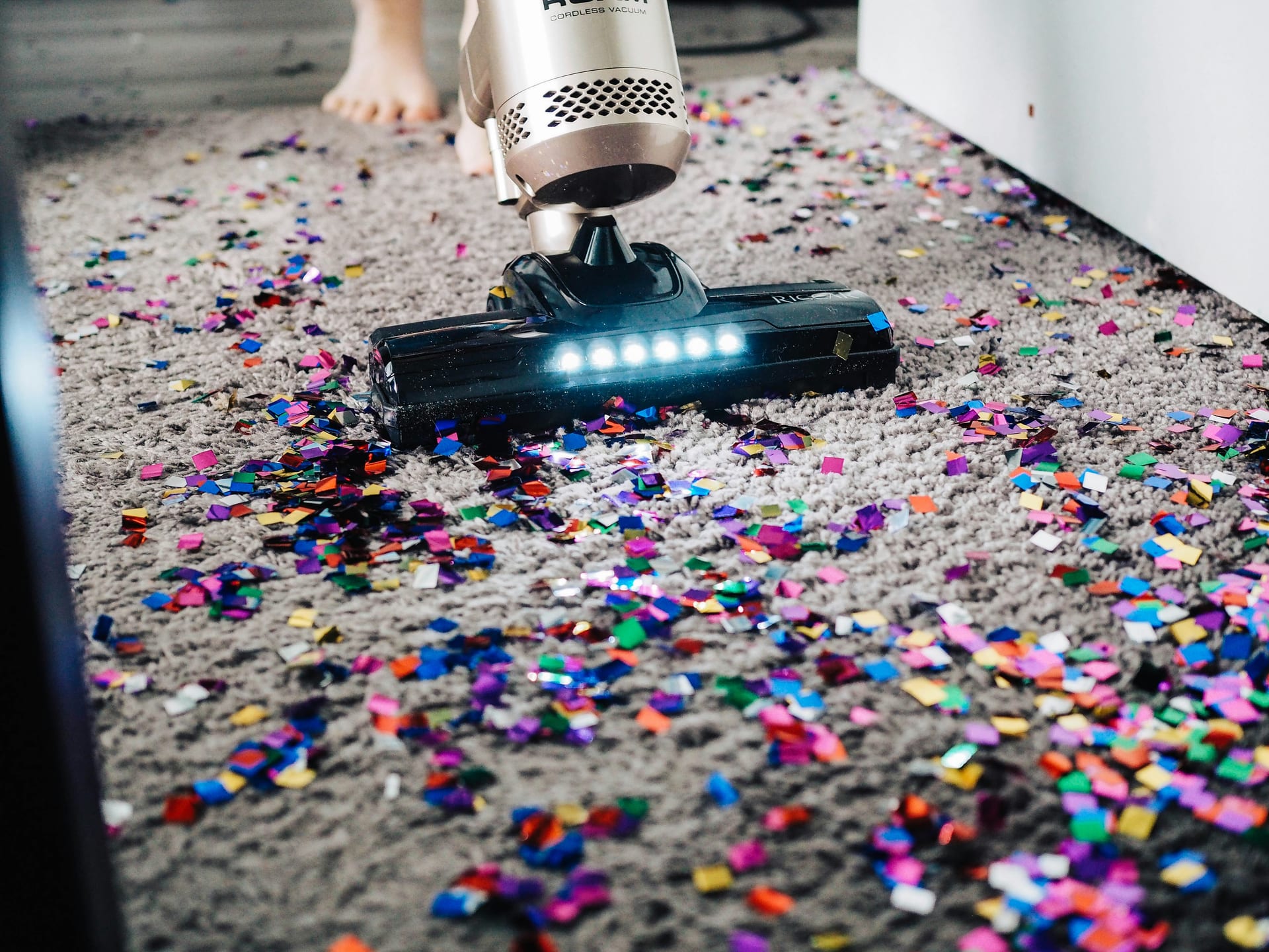 A vacuum head lifting dirt from a carpet, showing the cleaned strip behind it